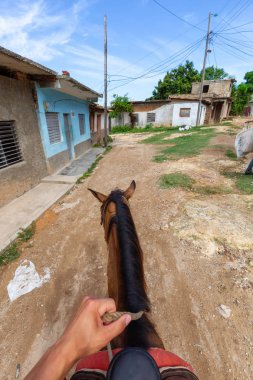 Trinidad, Küba - 12 Haziran 2019: Canlı güneşli bir günde küçük bir Küba Kasabasının sokaklarında bir atın üstüne binmek.