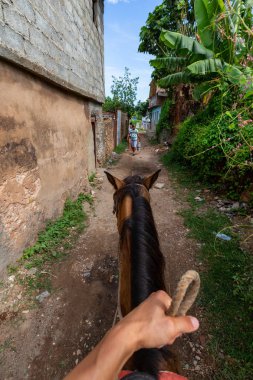 Trinidad, Küba - 12 Haziran 2019: Canlı güneşli bir günde küçük bir Küba Kasabasının sokaklarında bir atın üstüne binmek.