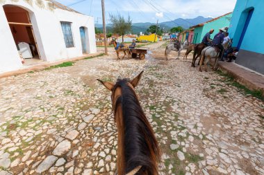 Trinidad, Küba - 12 Haziran 2019: Canlı güneşli bir günde küçük bir Küba Kasabasının sokaklarında bir atın üstüne binmek.