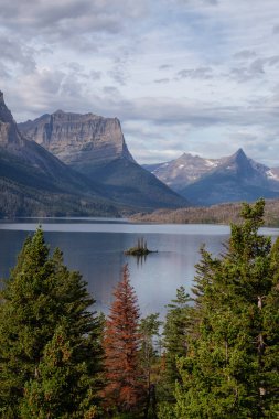Bulutlu bir yaz sabahı boyunca arka planda Amerikan Rocky Dağı manzaralı güzel bir Buzul Gölü Manzarası. Buzul Ulusal Parkı, Montana, ABD 'de çekildi..