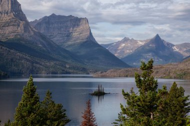 Bulutlu bir yaz sabahı boyunca arka planda Amerikan Rocky Dağı manzaralı güzel bir Buzul Gölü Manzarası. Buzul Ulusal Parkı, Montana, ABD 'de çekildi..