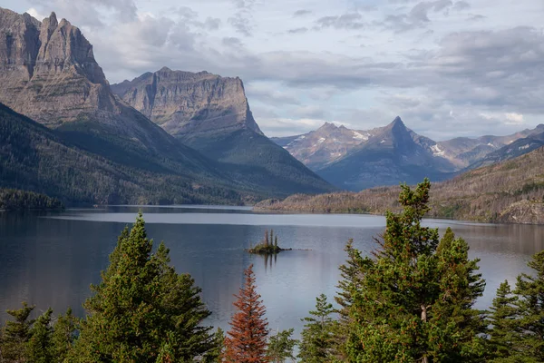 Bulutlu bir yaz sabahı boyunca arka planda Amerikan Rocky Dağı manzaralı güzel bir Buzul Gölü Manzarası. Buzul Ulusal Parkı, Montana, ABD 'de çekildi..