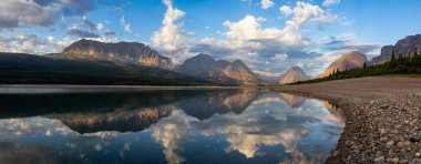 Beautiful Panoramic View of American Rocky Mountain Landscape during a Cloudy Morning Sunrise. Taken in Glacier National Park, Montana, United States. clipart