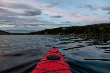 Buzul Gölü 'nde kayak yaparken bulutlu bir yaz günbatımında güzel Kanada Rocky Dağları etrafını sarmıştı. Yukarı Waterton Gölü, Alberta, Kanada.