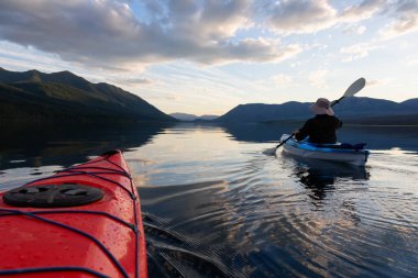 Maceracı Adam McDonald Gölü 'nde kayak yaparken güneşli bir yaz günbatımında arka planda Amerikan Rocky Dağları vardı. Buzul Ulusal Parkı, Montana, Usa 'da çekildi..