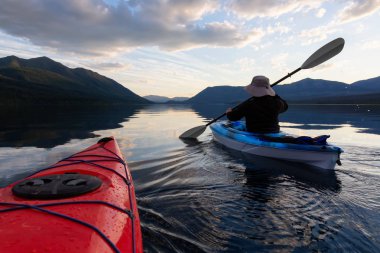 Maceracı Adam McDonald Gölü 'nde kayak yaparken güneşli bir yaz günbatımında arka planda Amerikan Rocky Dağları vardı. Buzul Ulusal Parkı, Montana, Usa 'da çekildi..