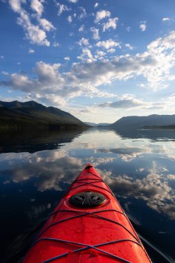 Kayaking in Lake McDonald during a sunny summer sunset with American Rocky Mountains in the background. Taken in Glacier National Park, Montana, USA. clipart