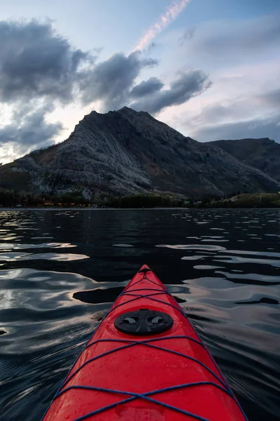 Buzul Gölü 'nde kayak yaparken bulutlu bir yaz günbatımında güzel Kanada Rocky Dağları etrafını sarmıştı. Yukarı Waterton Gölü, Alberta, Kanada.