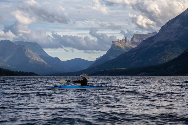 在多云的夏日落日 冒险的男子在冰河湖中划船 四周环绕着美丽的加拿大落基山脉 摄于加拿大艾伯塔省上沃特顿湖 — 图库照片