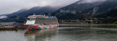 Juneau, Alaska, Amerika Birleşik Devletleri - 23 Eylül 2019: Bulutlu bir yaz sabahı küçük bir turistik kasabada park etmiş bir yolcu gemisinin güzel panoramik manzarası.