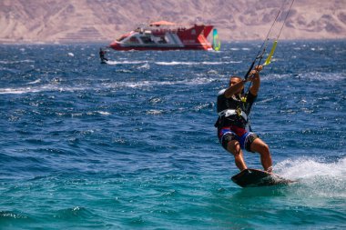 Eilat, İsrail - 12 Nisan 2019: Maceraperest insanlar güneşli bir günde Kızıl Deniz 'de su sporları ve uçurtmanın tadını çıkarıyorlar.