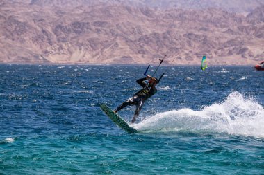Eilat, İsrail - 12 Nisan 2019: Maceraperest insanlar güneşli bir günde Kızıl Deniz 'de su sporları ve uçurtmanın tadını çıkarıyorlar.