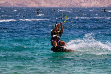 Eilat, İsrail - 12 Nisan 2019: Maceraperest insanlar güneşli bir günde Kızıl Deniz 'de su sporları ve uçurtmanın tadını çıkarıyorlar.