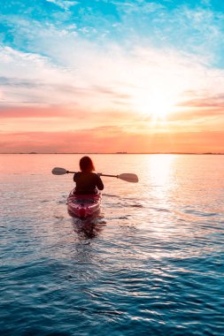 Renkli ve canlı bir günbatımında sakin sularda kano..