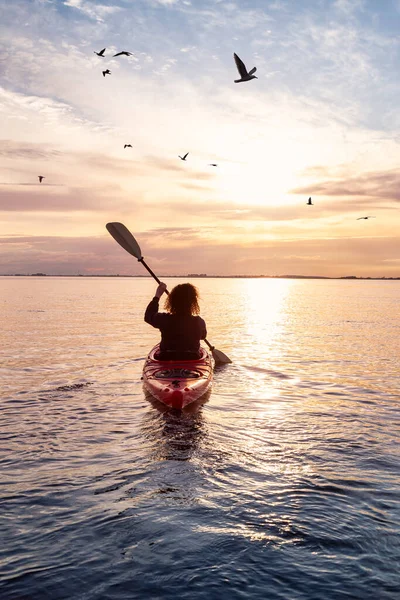 Sea Kayaking in calm waters during a colorful and vibrant sunset.