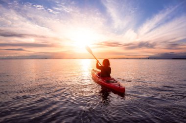 Renkli ve canlı bir günbatımında sakin sularda kano..