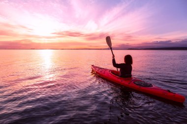 Renkli ve canlı bir günbatımında sakin sularda kano..