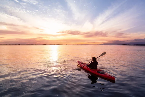 Sea Kayaking in calm waters during a colorful and vibrant sunset.