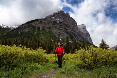 Bulutlu bir günde Kanada Kayalıklarında Kadın Sırt Çantası Yürüyüşü.