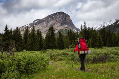 Bulutlu bir günde Kanada Kayalıklarında Kadın Sırt Çantası Yürüyüşü.