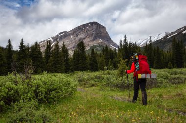 Bulutlu bir günde Kanada Kayalıklarında Kadın Sırt Çantası Yürüyüşü.