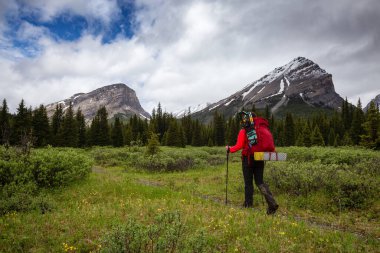 Bulutlu bir günde Kanada Kayalıklarında Kadın Sırt Çantası Yürüyüşü.