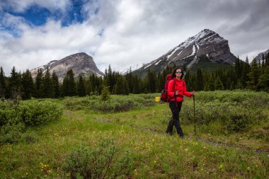 Bulutlu bir günde Kanada Kayalıklarında Kadın Sırt Çantası Yürüyüşü.