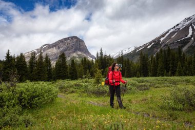 Bulutlu bir günde Kanada Kayalıklarında Kadın Sırt Çantası Yürüyüşü.