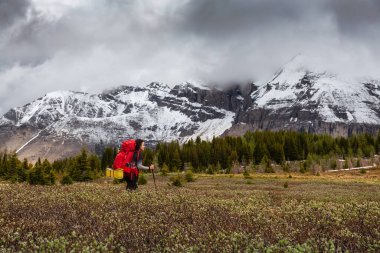 Bulutlu bir günde Kanada Kayalıklarında Kadın Sırt Çantası Yürüyüşü