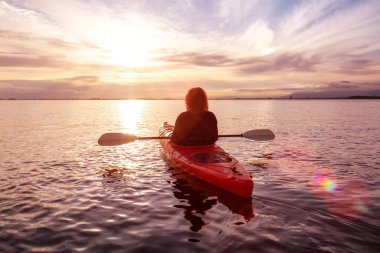 Renkli ve canlı bir günbatımında sakin sularda kano..