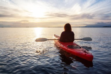 Renkli ve canlı bir günbatımında sakin sularda kano..