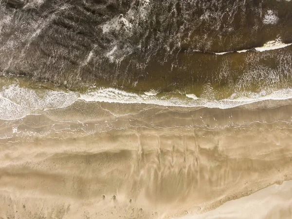 Luchtfoto van een zandstrand met golven afkomstig van de oceaan. — Stockfoto