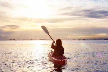 Renkli bir günbatımında kanoya binmek