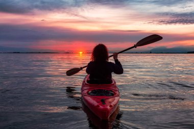 Renkli bir günbatımında kanoya binmek