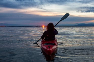 Renkli bir günbatımında kanoya binmek