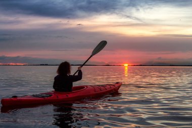 Renkli bir günbatımında kanoya binmek