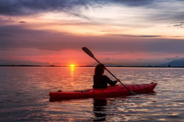Renkli bir günbatımında kanoya binmek