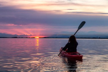 Renkli bir günbatımında kanoya binmek