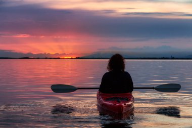 Renkli bir günbatımında kanoya binmek