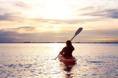 Renkli bir günbatımında kanoya binmek