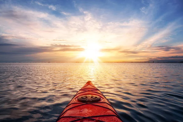 Kajakfahren in ruhigen Gewässern während eines farbenfrohen und lebendigen Sonnenuntergangs. — Stockfoto