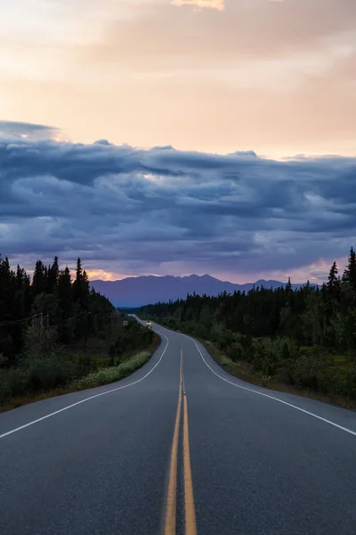 Belle vue sur une route pittoresque, Alaska Hwy, dans les Rocheuses du Nord lors d'un coucher de soleil nuageux spectaculaire. — Photo