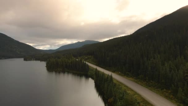 Вид на мирное озеро вдоль живописной дороги, окруженной горами — стоковое видео