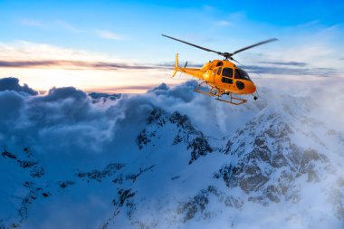 Sarı helikopter Rocky Dağları üzerinde uçuyor.