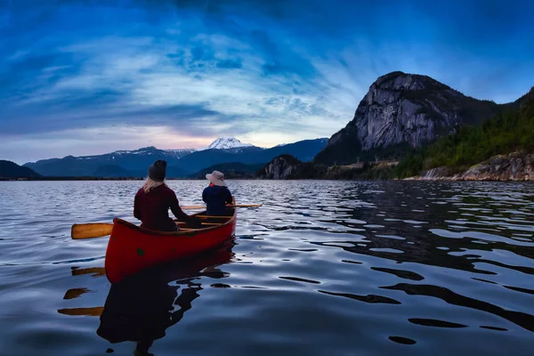 카누를 타고 산을 뒤로 하고 있는 사람들 — 스톡 사진