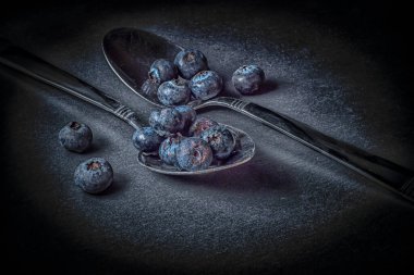 Kaşık üzerinde taze yabanmersini, koyu arka planda