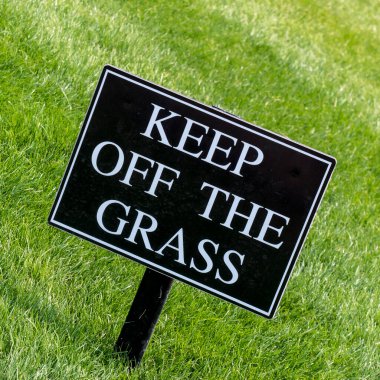Parkta iyi korunmuş bir çimenlikteki Çimlerden Uzak Dur tabelasına
