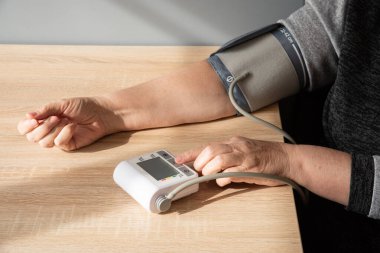 Kadın kendi kendine kan basıncını evde ölçüyor, elini yakın plan çekiyor..