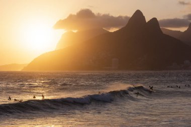 Güzel günbatımı manzara okyanus ve arka, Ipanema Plajı, Rio de Janeiro, Brezilya dağlardaki sörfçü ile