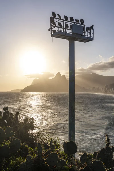 Beautiful sunset landscape by the ocean with lamp post and mountains on the back, Ipanema Beach, Rio de Janeiro, Brazil